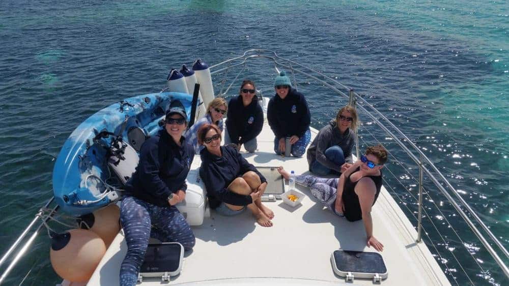 a group of people sitting next to a body of water