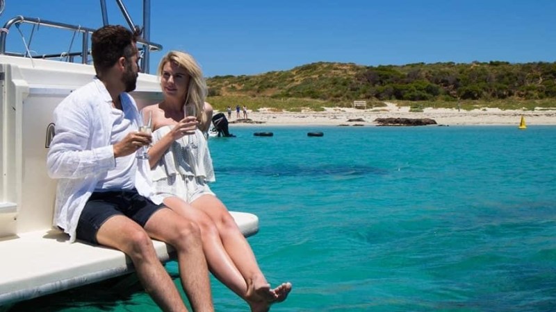 a man and woman sitting next to a body of water