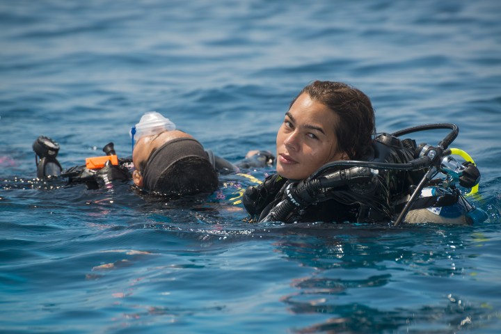 Two scuba divers rest in calm ocean water.