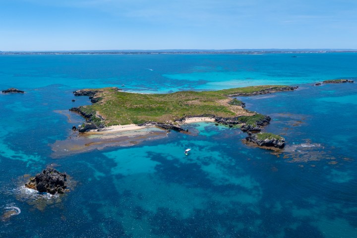 Aerial view of a small island in clear blue ocean waters.