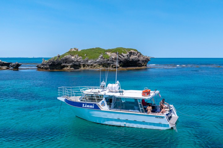 Boat named Lini on clear water with island in the background.