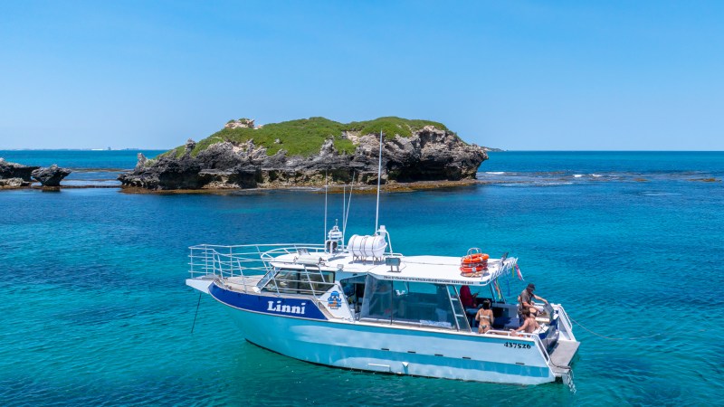 Boat named Linni on clear water with island in the background.