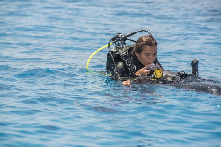 Scuba diver wearing gear floating on the ocean surface.