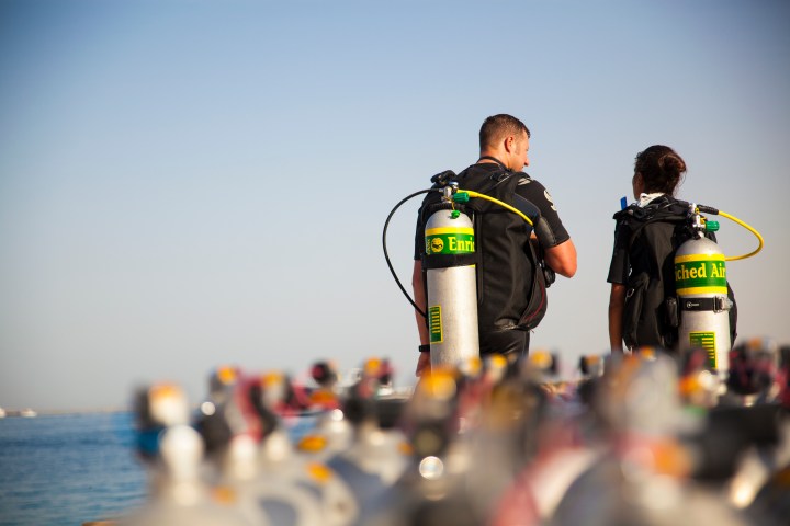 Two divers with tanks labeled 'Enriched Air' near the sea.
