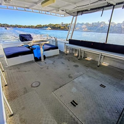 Empty boat deck with blue seating, lake view in background.