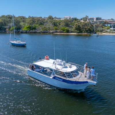 Small boat named Linni on a river with people aboard, near shoreline.