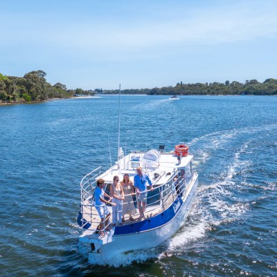 Group on a blue and white boat on a wide river, surrounded by trees.