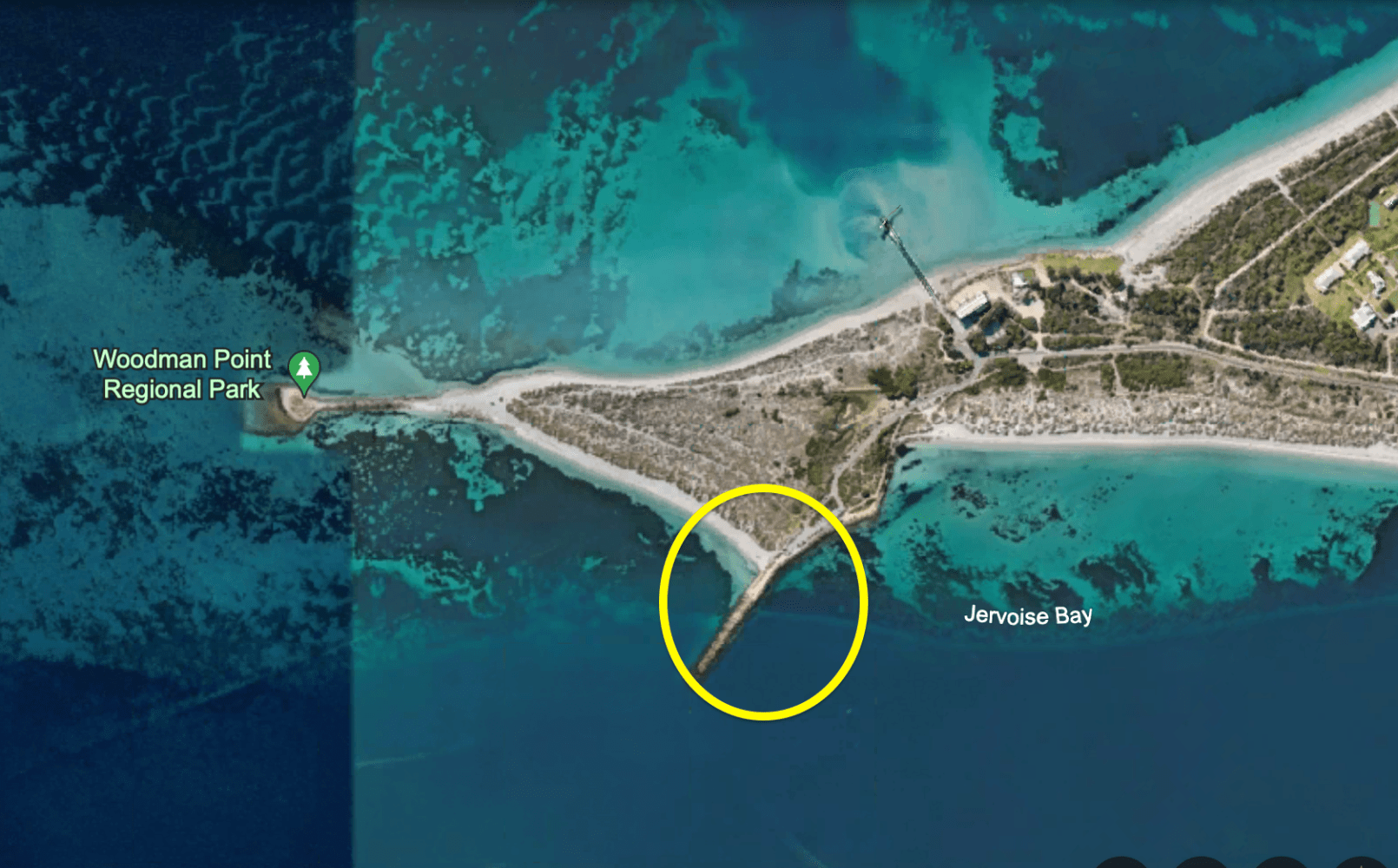 Aerial view of a coastal area with a pier extending into the water.