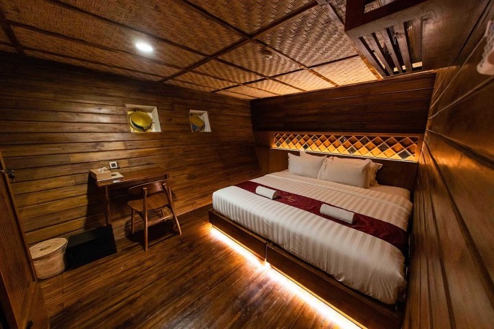 Cozy wooden room with a bed, desk, and warm lighting.